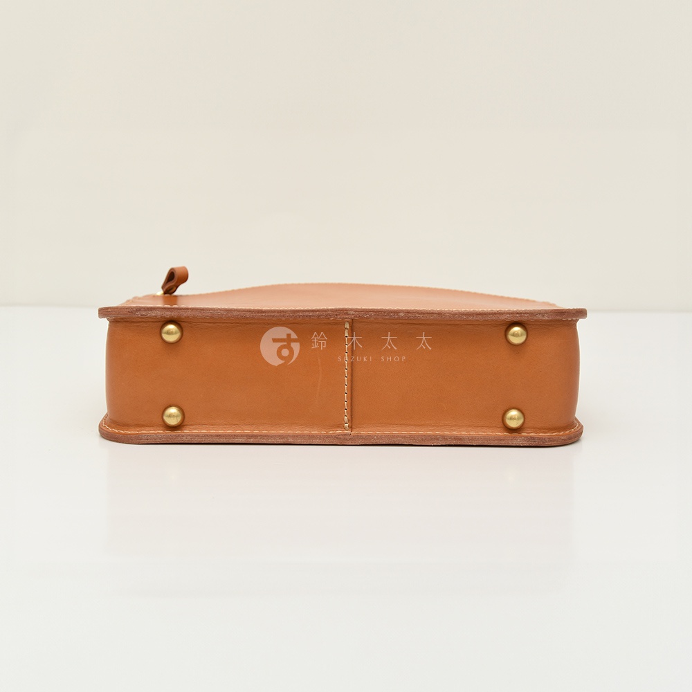 職人手作皮革兩用商務公事包，採棕色皮革製成，側邊有四個金屬卯釘裝飾，上方有提把，整體呈現簡潔俐落的商務風格。