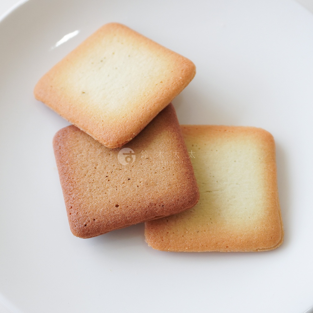 三塊方形餅乾疊放在白色盤子上，其中兩塊餅乾上有細小的標誌。