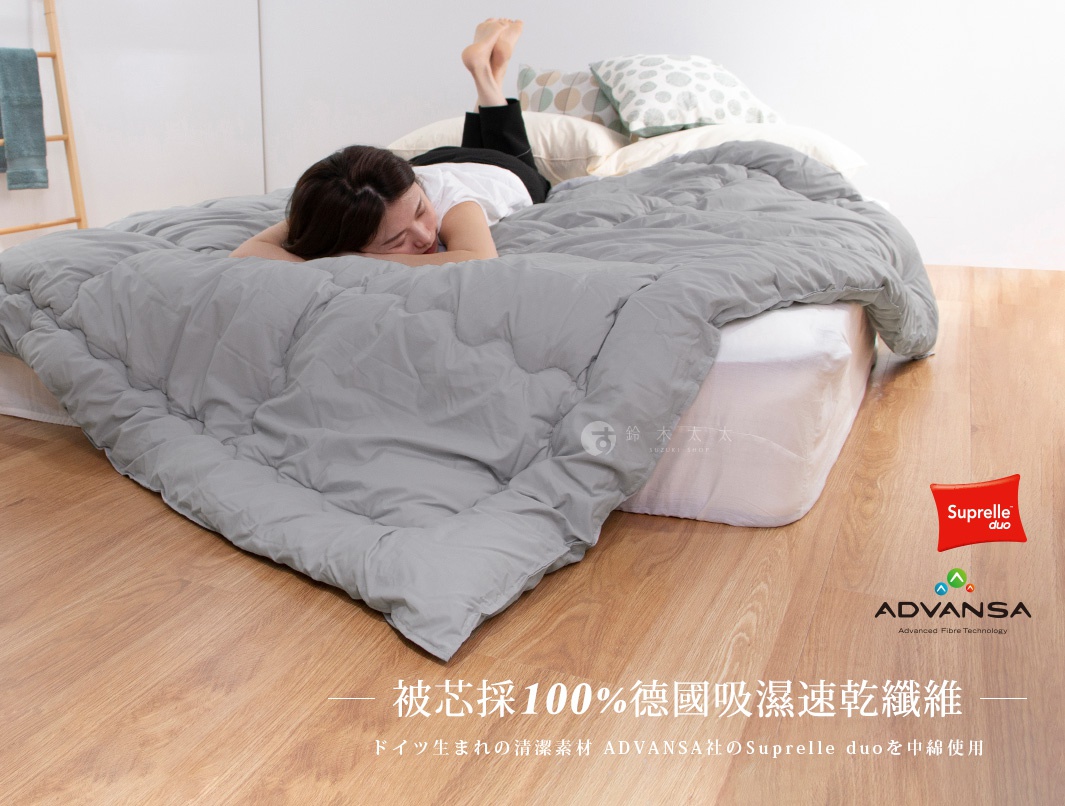 圖片中的文字「被芯採100%德國吸濕速乾纖維，德國生的清潔素材ADVANSADUPO」和「Suprelle duo」以及「ADVANS A Advanced Fibre Technology」。 一名女子仰躺在鋪有灰色被子的床上，被子上有菱格紋設計。床的下方和周圍是木質地板。