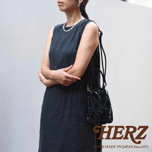 日本HERZ職人手作皮革Organ編織水桶包，搭配連帽長裙的女性模特兒，展現品牌標誌與手作 Since 1973 字樣。