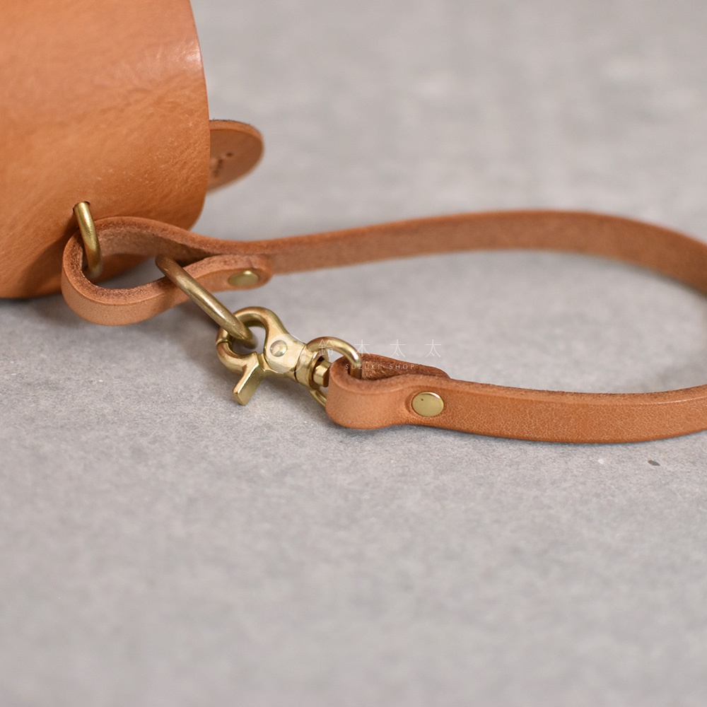 淺棕色皮革製作的Organ水壺套，特寫展示其手提帶、銅質掛鉤及鉚釘細節。