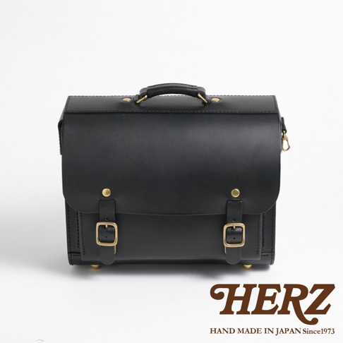 黑色皮革製成的橫式公事包，有頂部提把、兩個皮帶扣環以及黃銅色的金屬配件。
