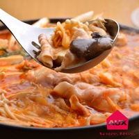 不鏽鋼濾湯火鍋杓撈起一勺豐富的火鍋料，包含豬肉片、金針菇、豆腐和香菇，湯頭呈現橘紅色，熱氣騰騰。