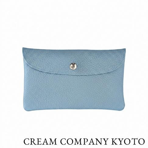 由日本品牌 CREAM COMPANY KYOTO 設計，這款淡藍色皮革多功能收納包呈現簡約長方形外觀，選用耐用且輕量的牛皮材質，包身中央配有一個精緻的金屬按扣，下方標示著 CREAM COMPANY KYOTO 品牌字樣，適合作為收納卡片、名片或隨身小物的手拿包使用。