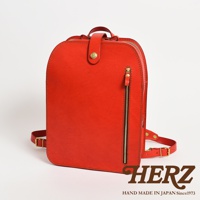 職人手作皮革商務休閒兩用後背包，採用亮紅色皮革，設有頂部提把、前方拉鍊口袋及可調整式肩帶，搭配金色五金配件。