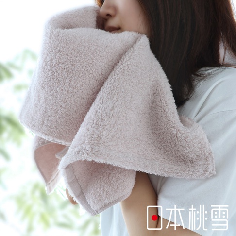 一女子用粉色蓬鬆毛巾擦拭臉部，毛巾的細膩絨毛清晰可見，右下角有「日本桃雪」的文字標識