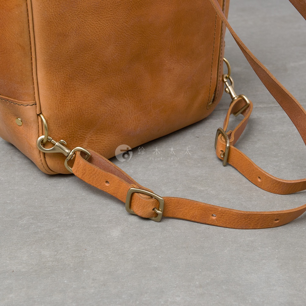 職人手作皮革Organ商務後背包的細節，展示了包包的棕色皮革材質、金屬扣環和可調節的皮革背帶。