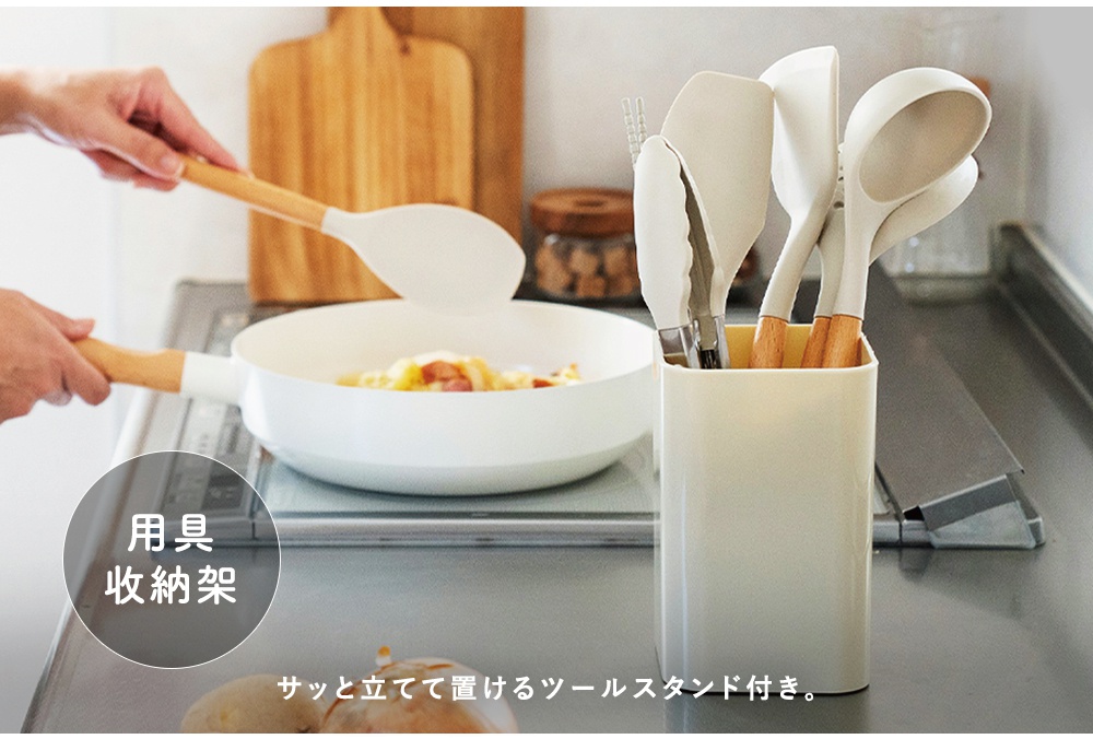 廚房用具11件組，包含白色矽膠鍋鏟、夾子、湯勺等，搭配木質手柄，收納於米白色直立式收納架中。