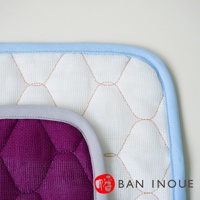 兩塊疊放的吸水墊，一塊為紫色，另一塊為白色，均為棉織材質，菱格紋縫線，搭配淺藍色和灰色滾邊。