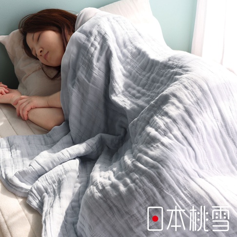 一位女子睡在床上，蓋著一件淺灰色的五層紗透氣被。