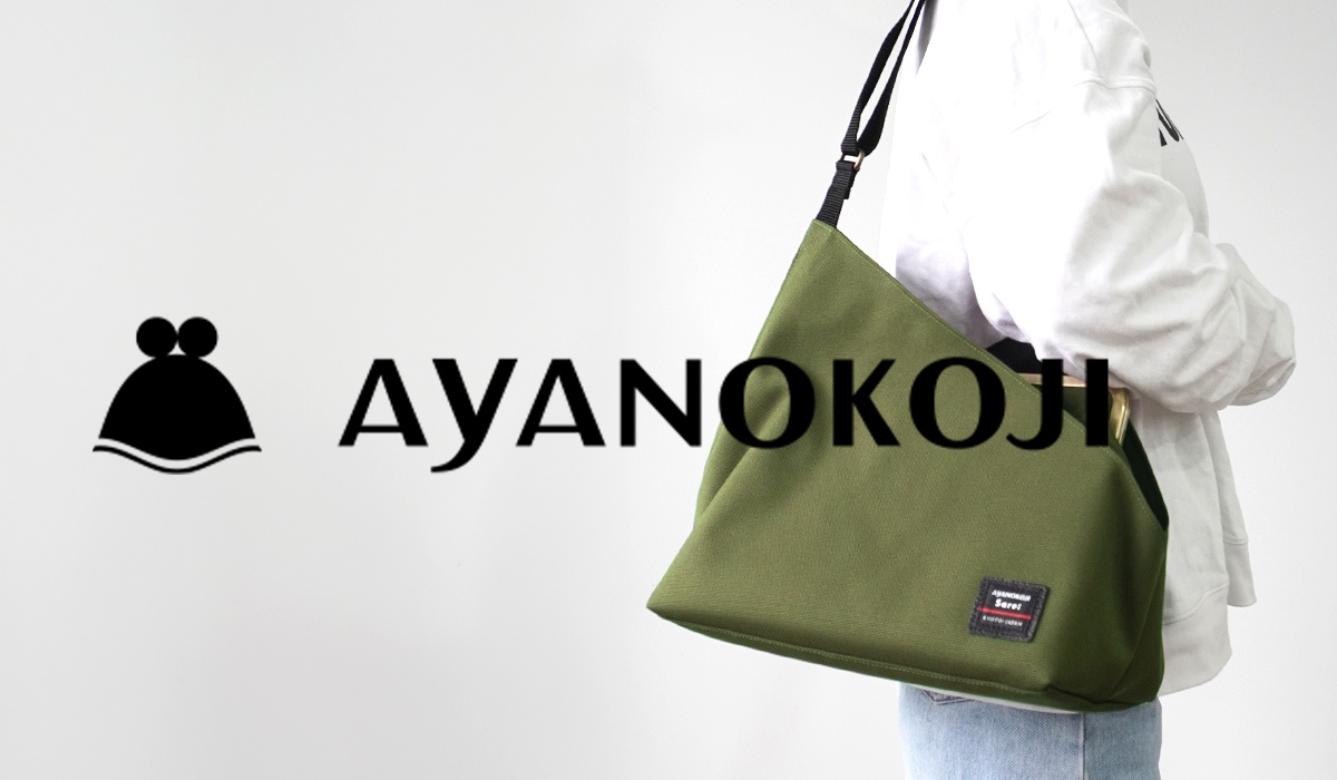 一位女士背著一個軍綠色的斜背包，包上印有「AYANOKOJI」字樣，左側有一個黑色圖標。
