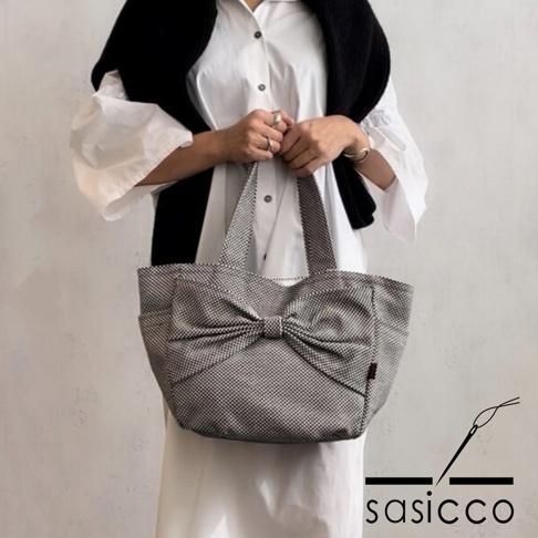 格紋刺子織托特包，前置蝴蝶結裝飾，兩側有外袋，背部有品牌標誌。