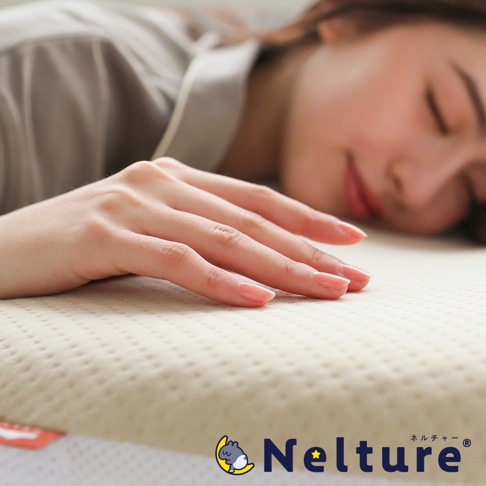 一張女子的手放在淺米色、帶有細緻網狀紋理的Q彈棉花糖枕上，背景是女子閉眼熟睡的臉部。枕頭表面中央有「Nelture」的品牌標誌。