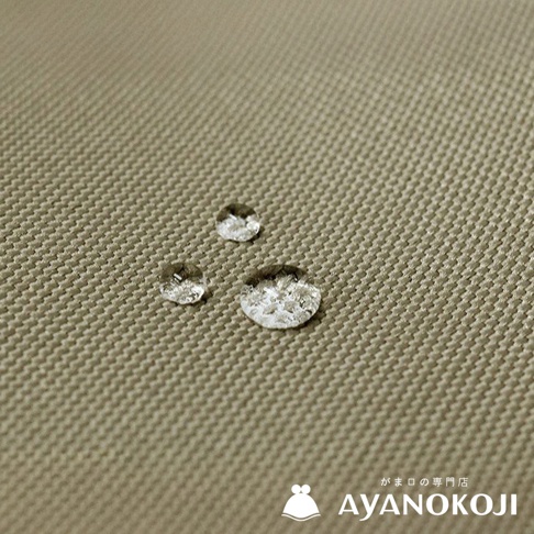 一塊米褐色織紋布料上有三顆水珠，右下角有「がま口の専門店 AYANOKOJI」的文字和一個白色水壺圖案。