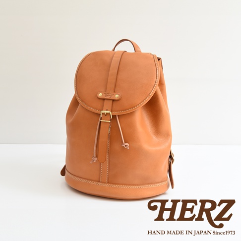 棕色皮革單扣束口後背包，設有可調節肩帶、頂部提把和金屬扣環。