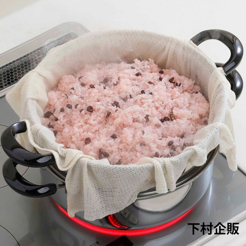 雙層蒸氣料理鍋，鍋身為不鏽鋼材質，配有兩個黑色防燙提把。鍋內置有白色蒸布，盛有粉紅色、帶有紅豆的米飯，上方冒出蒸氣。
