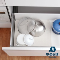 打開的廚房抽屜中，一個淺米色珪藻土墊上擺放著不銹鋼濾網、一個不銹鋼盆、兩個白色帶蓋的鍋具，以及一個藍色鍋蓋的藍色鍋子。