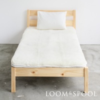 單人床架上鋪著厚實的白色美麗諾羊毛保暖墊，墊上有一顆白色枕頭。