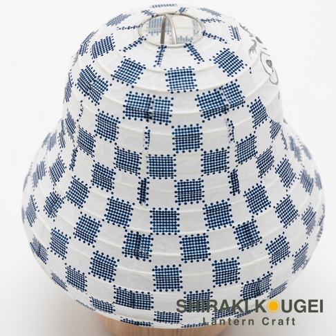 白色紙質提燈，表面印有藍色棋盤格紋飾，頂部有金屬支架，底部為木製底座。