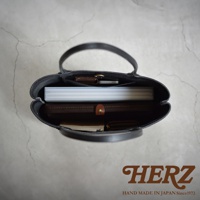 HERZ HAND MADE IN JAPAN Since1973，黑色皮革托特包內部，可見文件夾、筆記本、手機及零錢包。