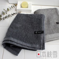 兩條厚實的毛巾，一條深灰色，一條淺灰色，皆為純棉材質，帶有品牌標籤。
