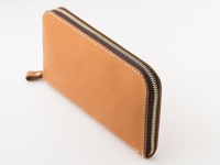 職人手作棕色皮革長夾，配有金色拉鍊和細緻縫線，左側有一個小巧的皮革拉環。