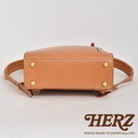 一張特寫圖，顯示職人手作皮革商務電腦後背包 R-25 的底部及部分側面。後背包為經典的駱駝色皮革，帶有精緻的縫線和黃銅色的鉚釘裝飾。