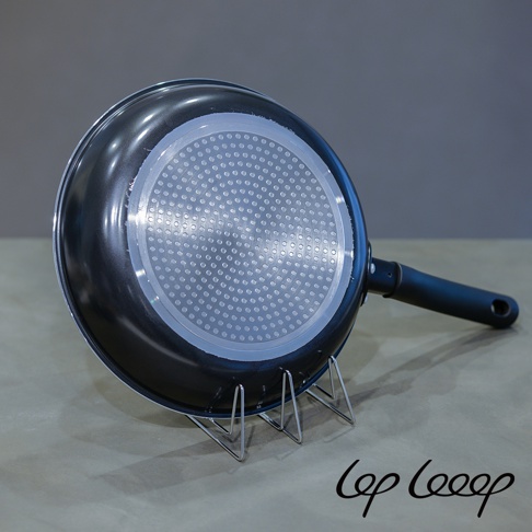 銀色不鏽鋼砧板架，支架呈現三角形結構，穩固支撐著黑色鍋底帶有圓形紋路的鍋具。