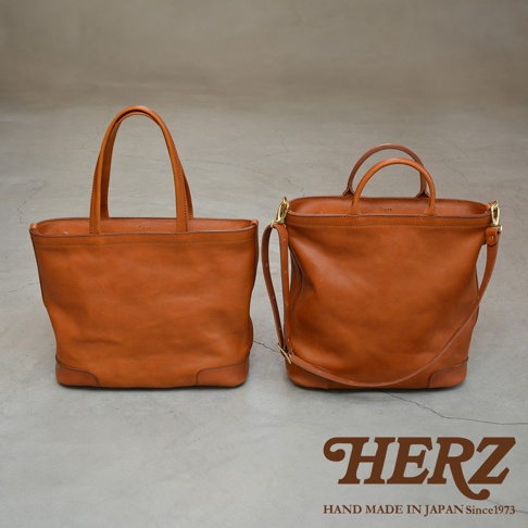 兩個棕褐色皮革托特包，其中一個有肩帶，皆為手工製作。