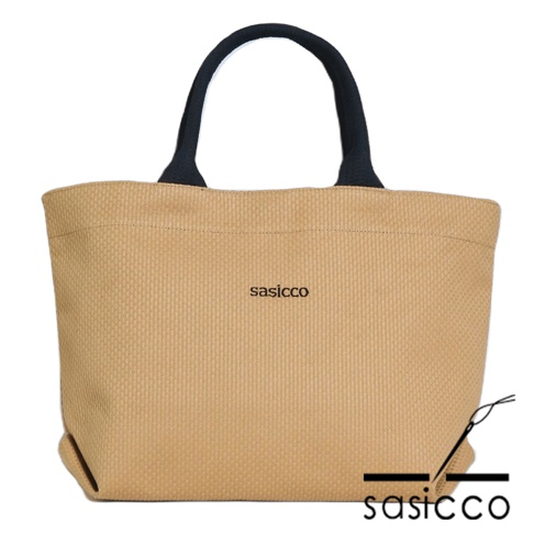 三河木綿刺子織經典托特包，米褐色主體搭配黑色提把，織紋清晰，正面繡有黑色品牌標誌。