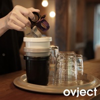 疊放的黑色、淺灰色和白色琺瑯馬克杯，杯口朝上，手中握持著一個紫色和銀色的握把，旁邊堆疊著透明玻璃杯，均放在金屬托盤上。