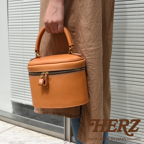 職人手作皮革圓筒型化妝手提包，天然皮革，圓潤厚實的包身，拉鍊開合，頂部有提把。