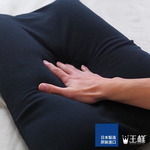 深藍色純色枕套，材質柔軟，表面有細微紋理。一隻手輕輕按壓在枕頭上，展現其柔軟度。