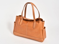 棕色皮革橫式肩背包，兩側有外袋，袋身縫線明顯，風格簡約。