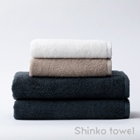 堆疊的泉州匹馬棉浴巾，由上至下分別為白色、淺褐色和深藍色，質地柔軟。