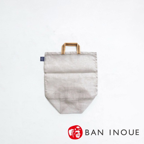 淺灰色帆布提把蔬果收納袋，具有木質編織提把，袋身有明顯紋理，左側有藍色品牌標籤。