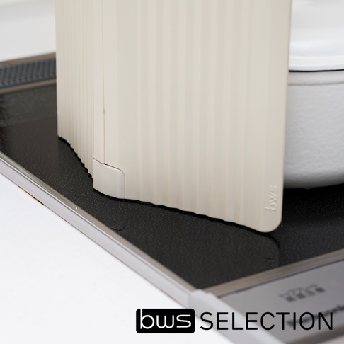 米色六片式摺疊隔板，表面有垂直紋路，置於爐灶黑色防油墊上，右側為白色鍋具。