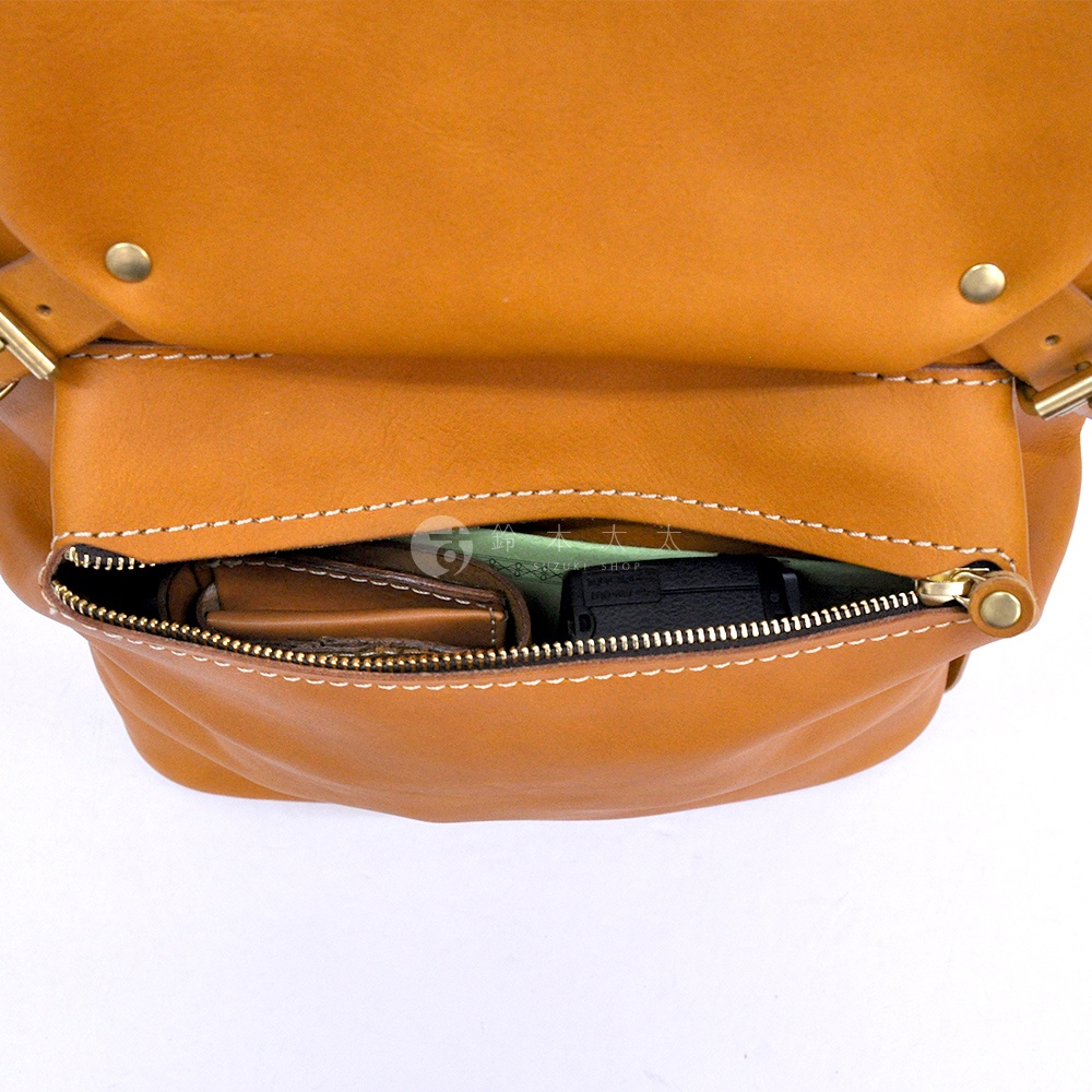 職人手作皮革多口袋後背包 R-135，展示其主隔層內部，一個拉鍊口袋內有棕色皮夾和黑色物品，背包材質為淺棕色皮革，縫線清晰。