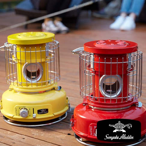 一黃一紅兩台卡式瓦斯暖爐，皆為金屬材質，圓柱形機身，頂部有導熱散熱孔，周圍環繞著防護金屬網罩，底部有旋鈕與開關，其中紅色暖爐底部有「Sengoku Aladdin」品牌標誌。