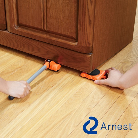 橙色迷你家具起重器，帶有銀色金屬手柄，用於抬起深棕色木製家具的底部。