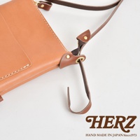 職人手作皮革直式隨身單肩包，展示皮革的自然紋理與縫線細節，配有深棕色皮革背帶和拉鍊。