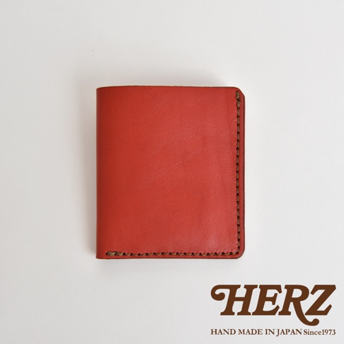 HERZ 職人手作紅色皮革二折式薄型卡片鈔票夾，側面縫線細緻，標示 HAND MADE IN JAPAN Since1973