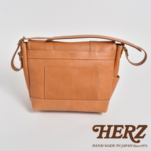 職人手作皮革復古郵差包，採用天然棕色皮革製作，包身有縫線細節，前有貼袋設計，搭配可調節的肩帶，整體風格簡約大方。