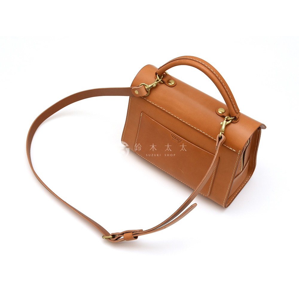 HERZ 品牌棕色皮革多功能收納單肩包，具有手提把和可拆卸的肩背帶，包包正面有品牌標誌與日文 SUZUKI SHOP 字樣。