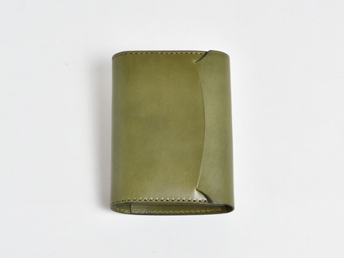 橄欖綠皮革A6記事本書套，表面平整，邊緣縫線細緻，一側邊緣有弧形設計。