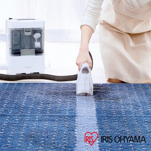 織物清潔機 RNS-300，白色主機連接黑色軟管，由一人手持透明吸頭，清潔藍色條紋地毯。