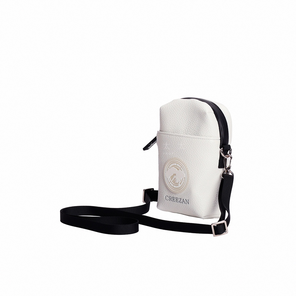 白色皮革紋理高爾夫迷你側背收納包，正面有品牌圓形標誌和文字。包身頂部有黑色拉鍊，配有黑色可調節斜挎帶，帶有金屬扣。