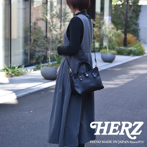 黑色皮革迷你托特包，配有金色旋轉鎖扣和可拆卸肩帶。包包由職人手工製作，展現簡約經典的設計。