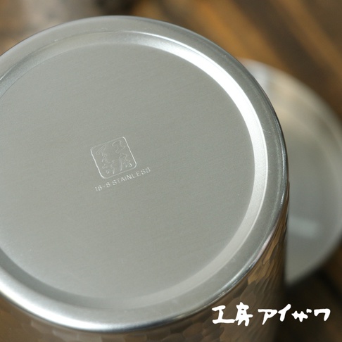 不鏽鋼錘目紋茶葉罐底部，銀色金屬材質，刻有方形圖案及「18-8 STAINLESS」字樣。