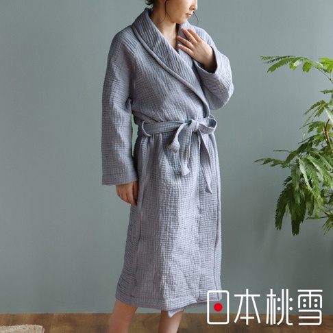 一位女性穿著淺灰色雙面紗布立體織紋輕質浴袍，腰間繫著同色腰帶，浴袍質料輕薄，展現休閒風格。